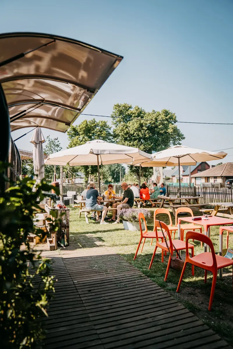 Pad naar het terras met rode stoelen en parasols