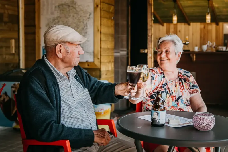 Ouder koppel klinkt met een glas bier in de overkapping