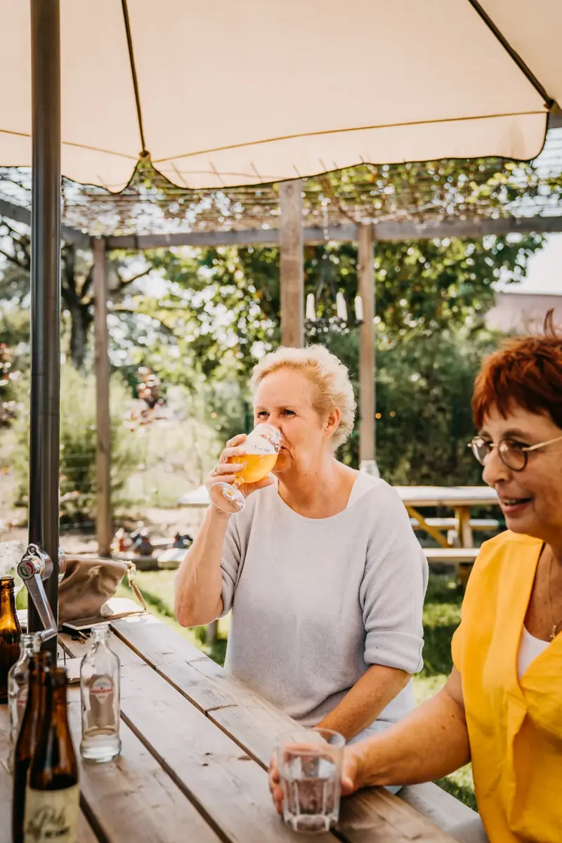 Twee vrouwen drinken een biertje onder de parasol